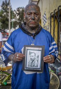 Pizarrón es uno de los fundadores del Chilangos Lowbike Club de México. Tiene la mayor parte del cuerpo tatuada y sostiene en la foto una imagen suya con la cara todavía sin tatuar. El grupo usa bicicletas modificadas. Foto: Jair Cabrera Torres/dpa