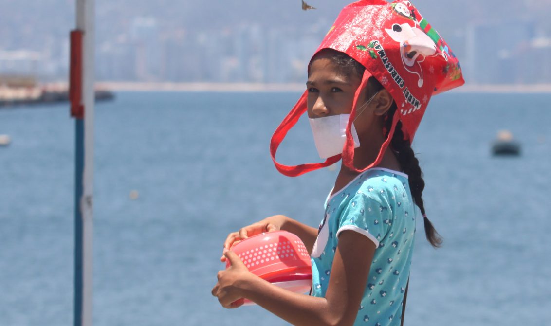 Acapulco,Gro/25Mayo2020/ Una niña se cubre la cabeza con una bolsa ante el intenso calor del medio día de ayer, mientras hace fila para recibir un porción de alimentos en la cocina comunitaria instalada en el Malecón de Acapulco. Foto: Jesús Trigo