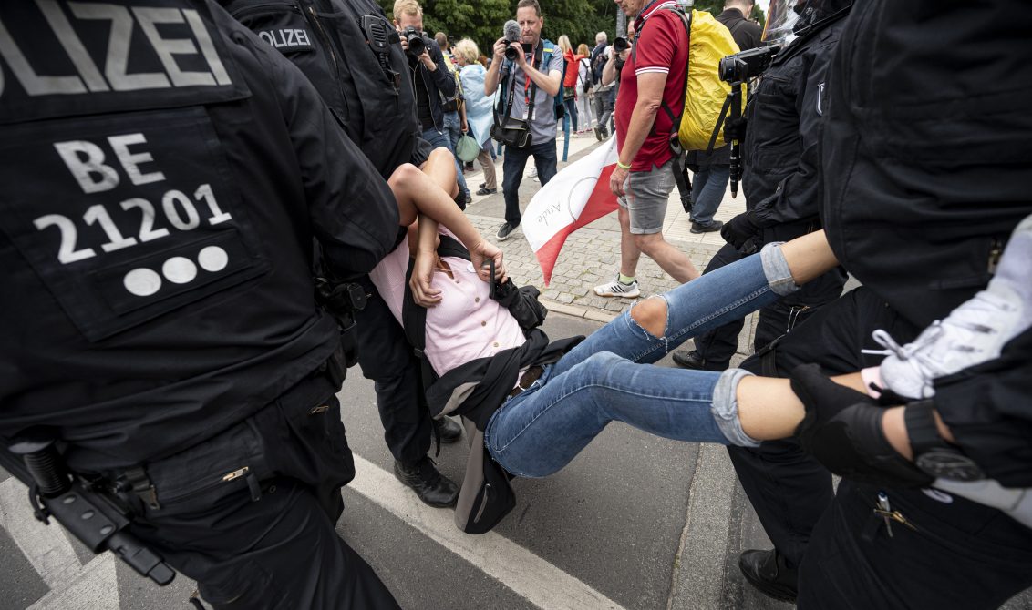 01 August 2021, Berlin: Policemen detain a woman taking part in an unannounced demonstration against the Coronavirus measures despite a ban on protests. Photo: Fabian Sommer/dpa
