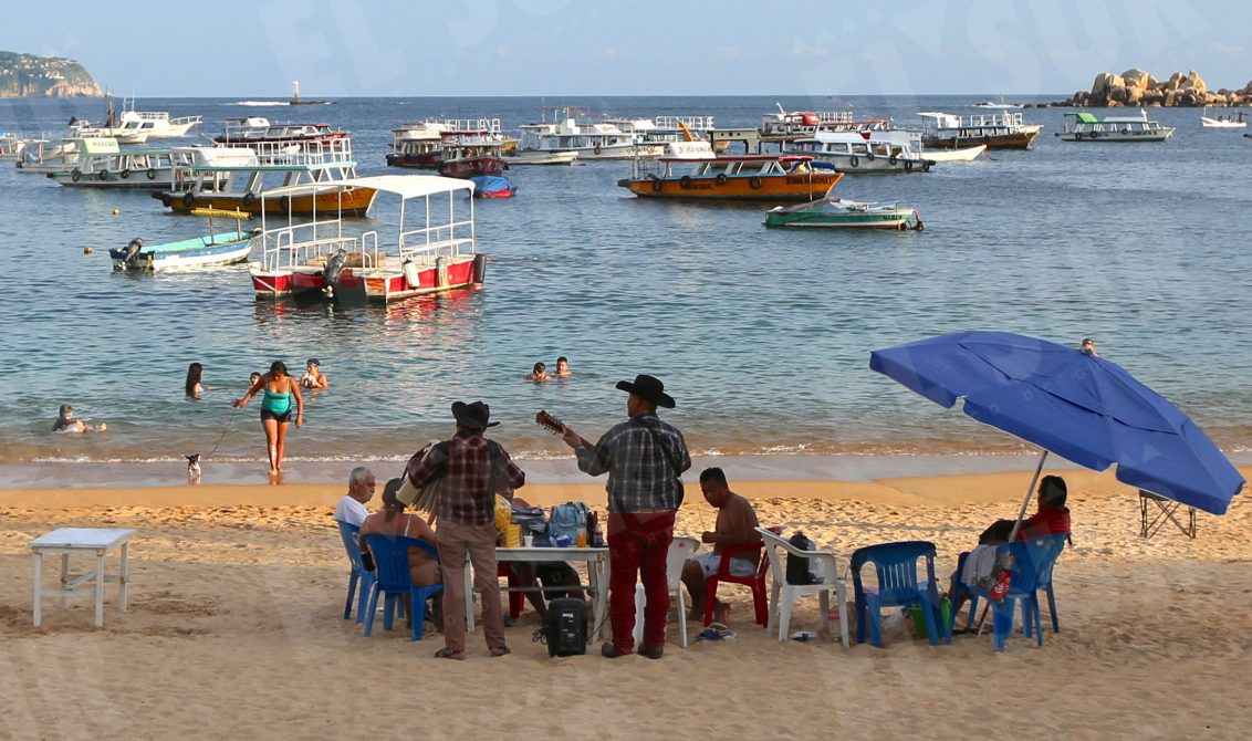 Acapulco,Gro/120Octubre2021/ Un dueto de músicos norteños le cantan a una familia de vacacionistas en la playa de Caleta en Acapulco, la tarde de ayer. Foto: Jesús Trigo