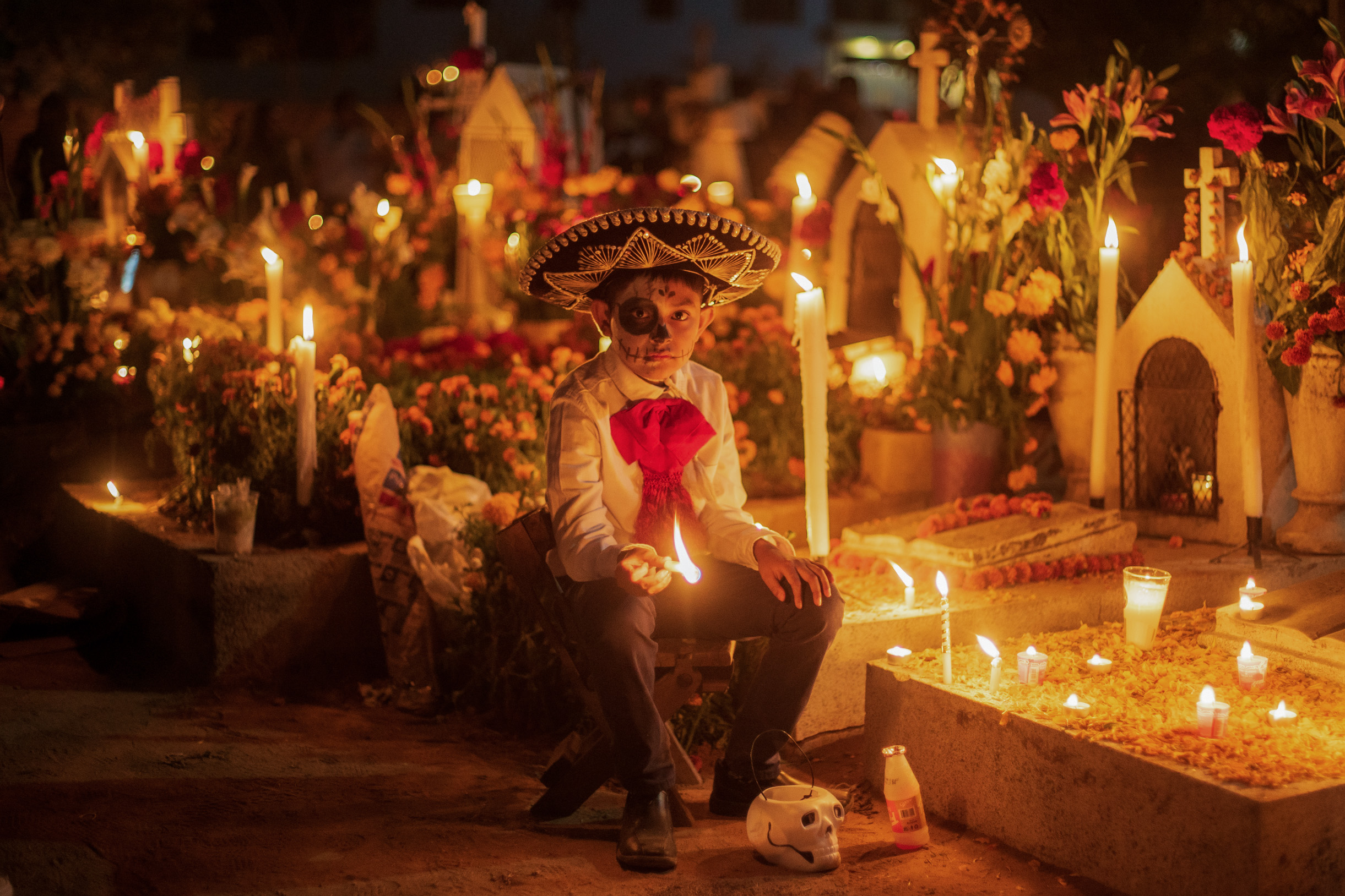 31 October 2022, Mexico, Oaxaca: A boy in costume holds a candle at a decorated cemetery on All Saints' Day which celebrates the Day of the Dead. Photo: Felipe Perez/dpa