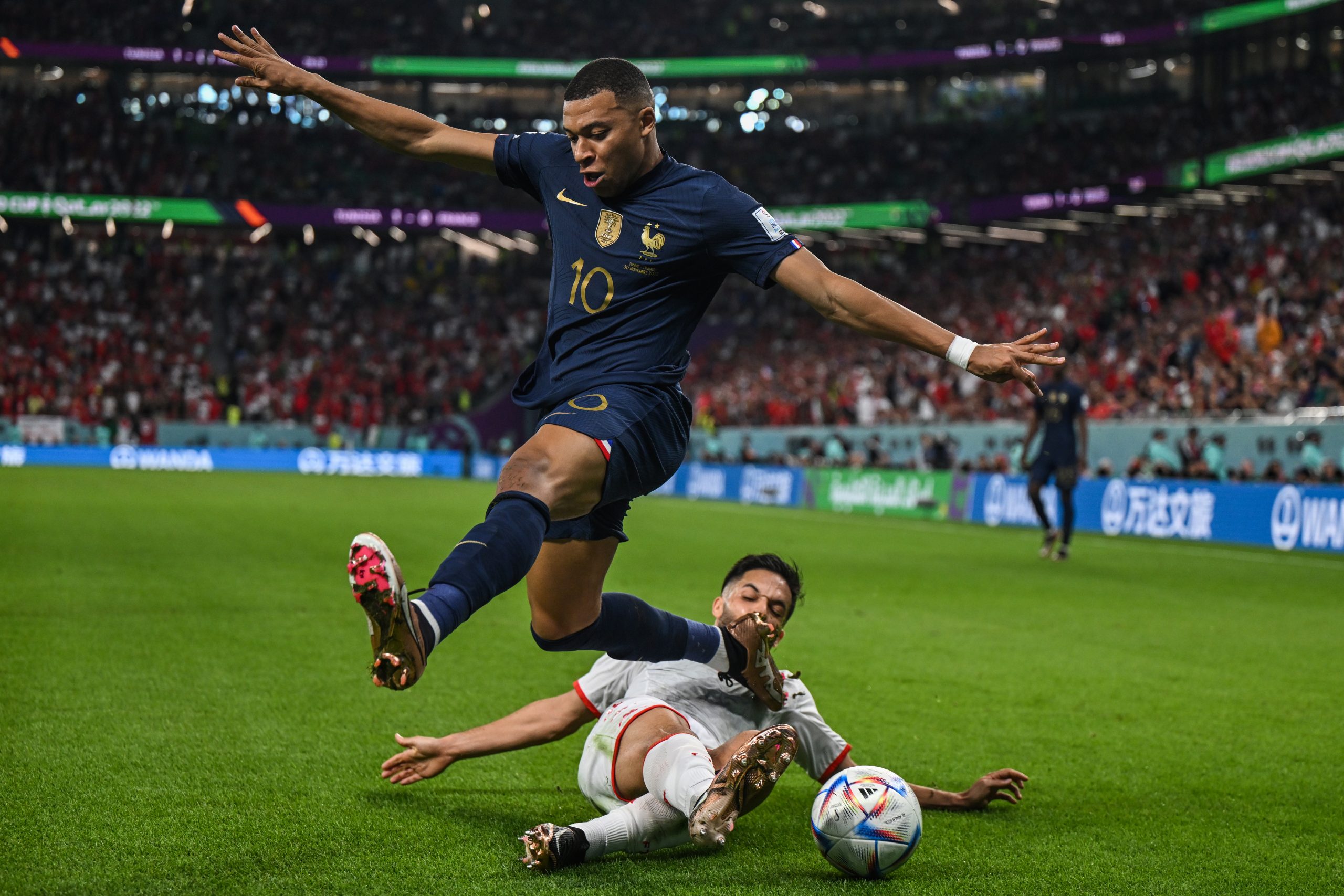 30 November 2022, Qatar, Al Rayyan: France's Kylian Mbappe (L) and Tunisia's Wajdi Kechrida battle for the ball during the FIFA World Cup Group D soccer match between Tunisia and France at the Education City Stadium. Photo: Robert Michael/dpa
