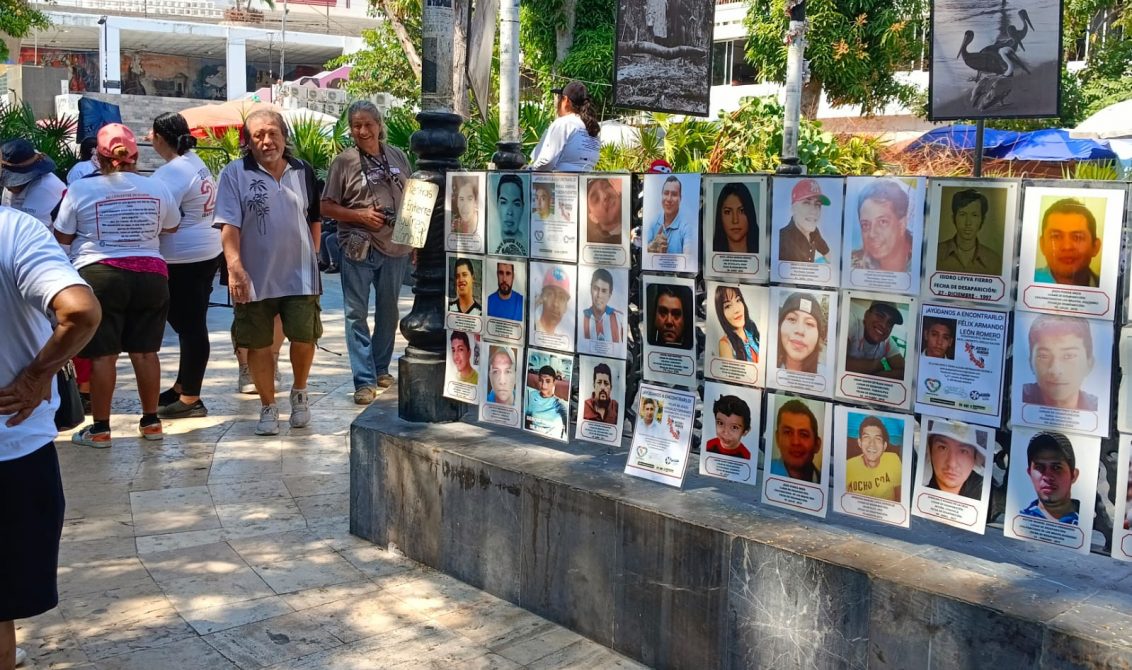 Transeúntes observan la exposición fotográfica de personas desaparecidas que el sábado pusieron integrantes de la Colectiva Memoría Verdad y Justicia en el Zócalo de Acapulco. Foto: Aurora Harrison