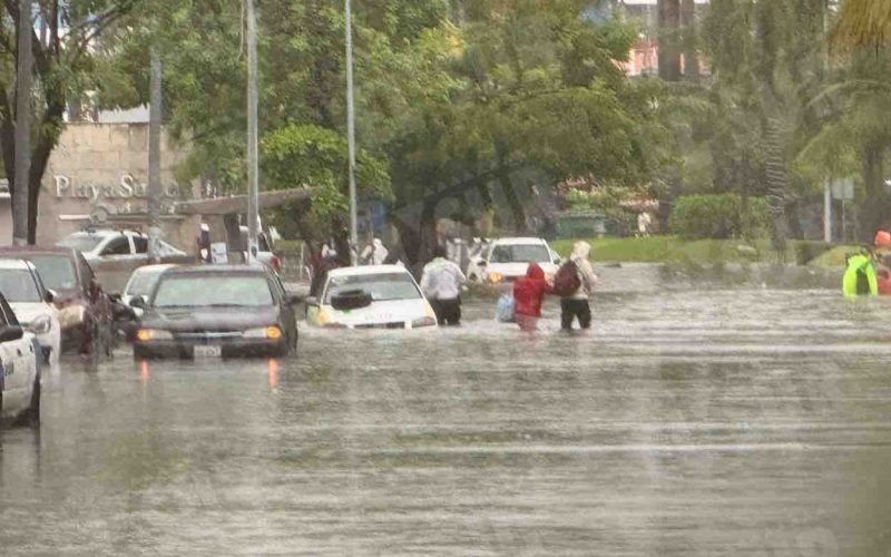 Personas caminan por la inundada avenida Costera de Acapulco, tras una hora de lluvia. Foto: Jacob Morales