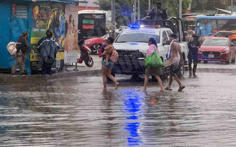 Personas caminan por la inundada avenida Costera de Acapulco, tras una hora de lluvia. Foto: Jacob Morales