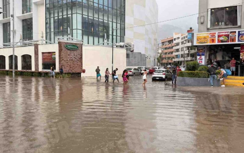 Personas caminan por la inundada avenida Costera de Acapulco, tras una hora de lluvia. Foto: Jacob Morales
