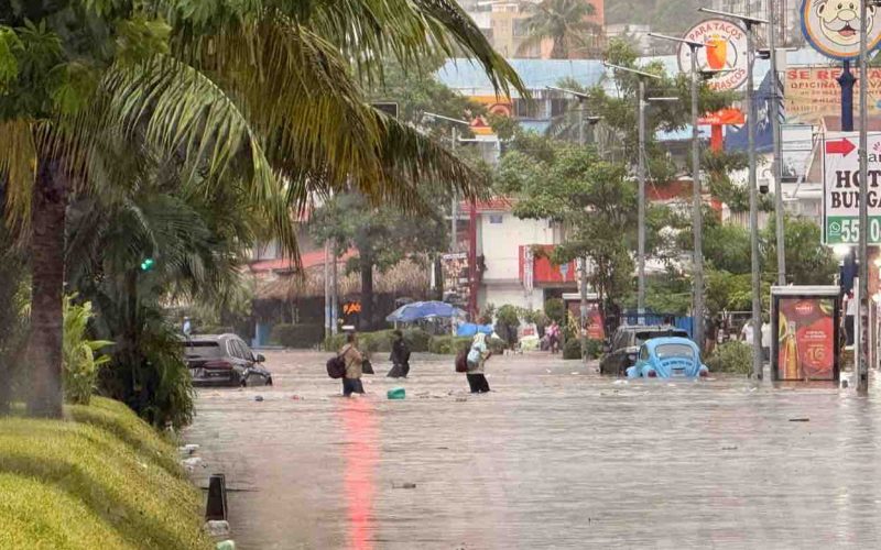Personas caminan por la inundada avenida Costera de Acapulco, tras una hora de lluvia. Foto: Jacob Morales