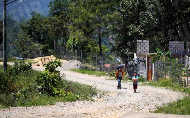 Un niño con una cubeta de nixtamal y un adulto con una bolsa negra con ropa caminan por la localidad de Rincón de Alcaparrosa, donde 45 familias salieron desplazadas por temor a la violencia luego de que militares y policías estatales que permanecían en la zona se retiraron la mañana del miércoles. Hicieron lo propio vecinos de la comunidad Agua Hernández. Foto: Jesús Eduardo Guerrero